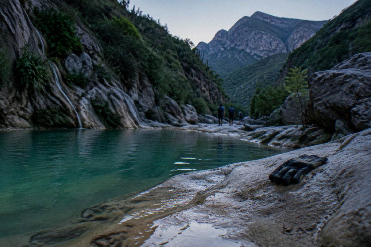 Narrow limestone canyon with turquoise water pooling between smooth rock walls