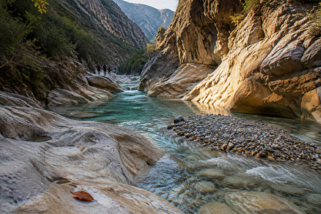 A narrow limestone canyon with clear water flowing between polished rock walls