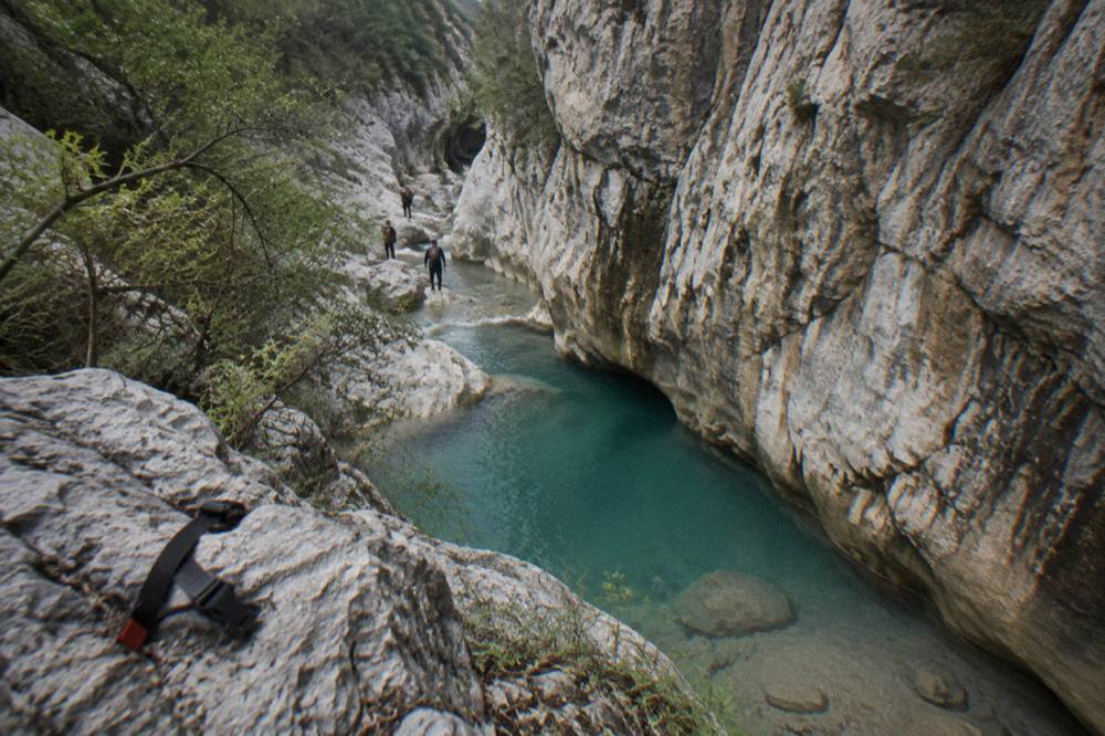Tall limestone canyon walls with a turquoise pool at the base near Monterrey