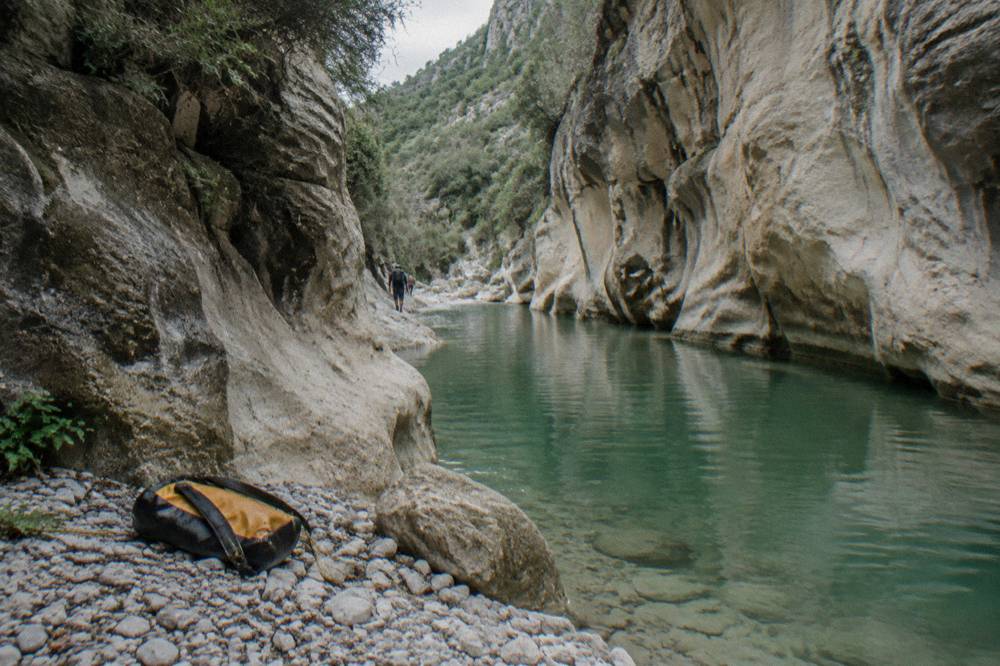 A deep canyon passage with still green water between smooth rock walls