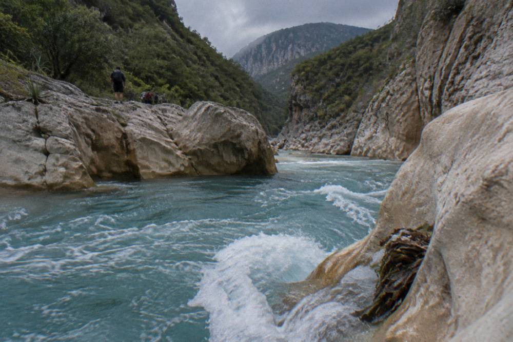 Turbulent turquoise water flowing between polished limestone walls in a narrow canyon passage
