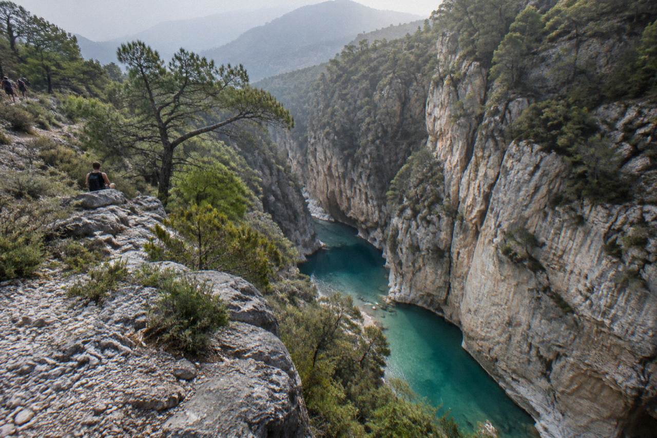 Narrow limestone canyon with turquoise water pooling between tall rock walls