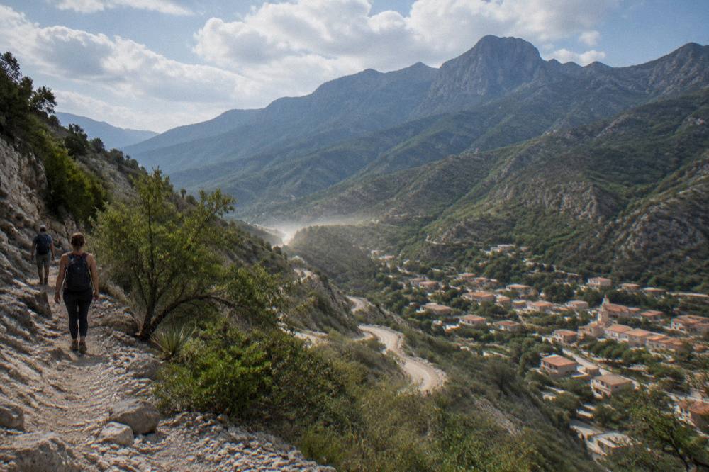 A wide valley of green mountains under a partly cloudy sky