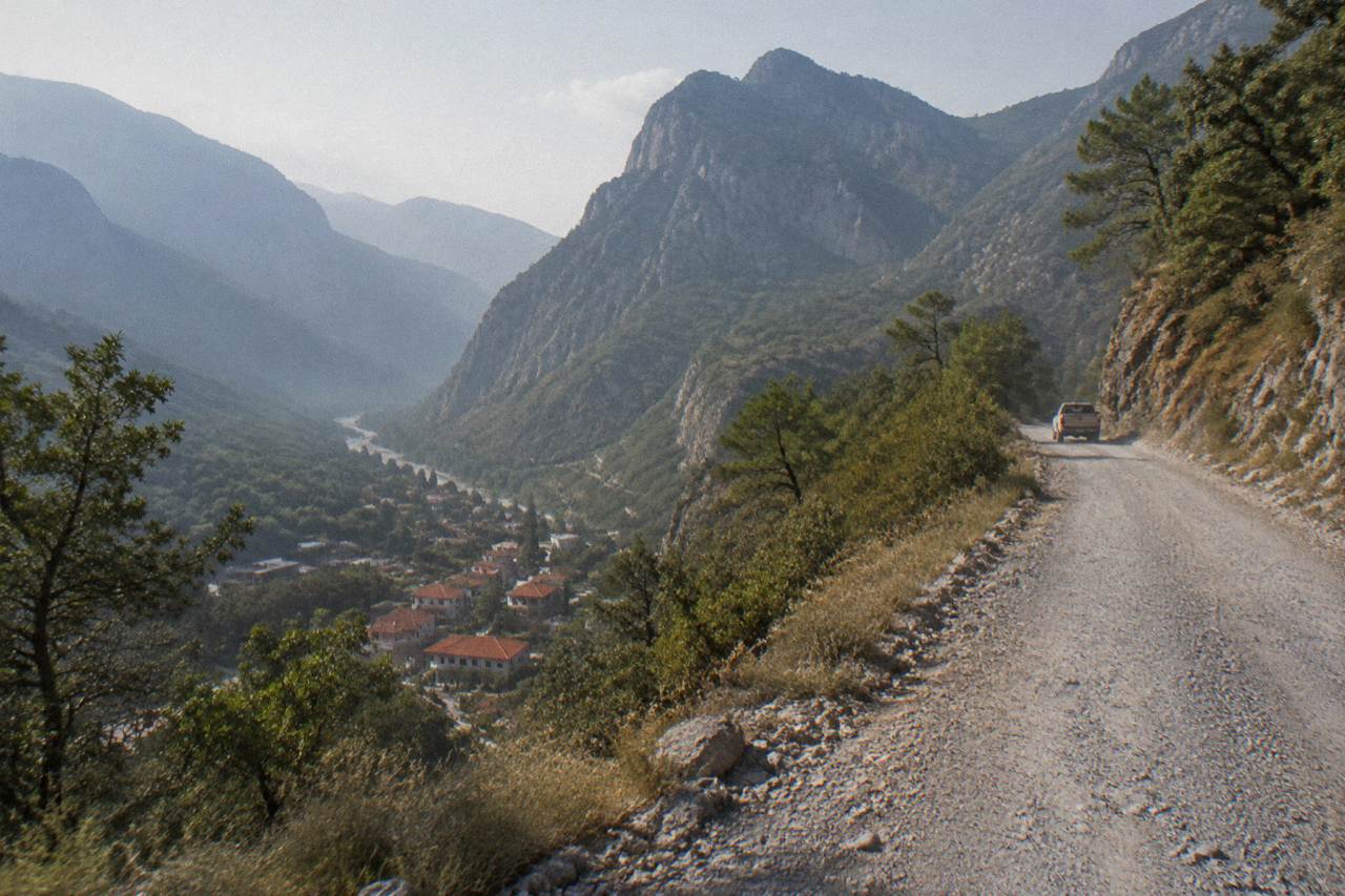 Mountain road winding toward forested peaks above a small town in northern Mexico