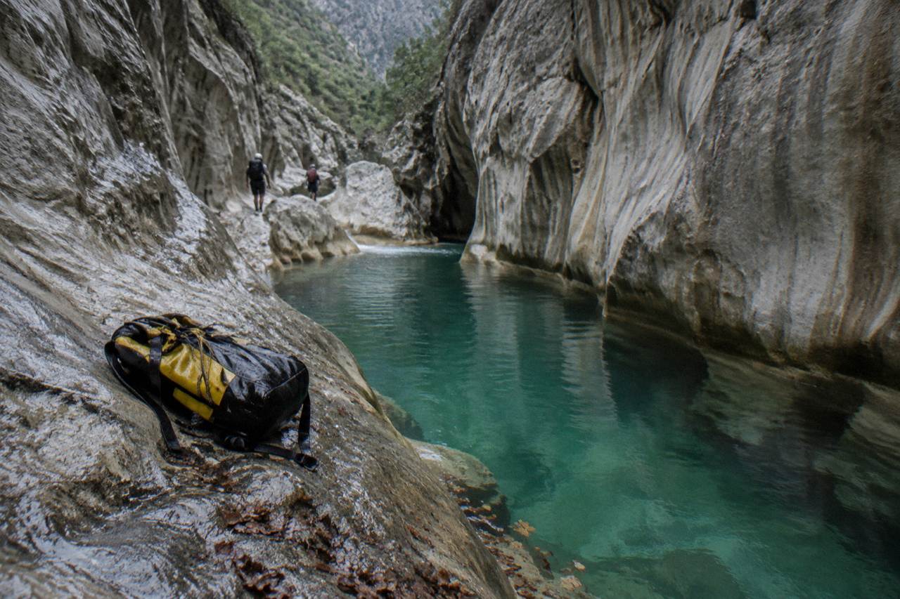 Narrow limestone canyon with turquoise water pooling between tall rock walls
