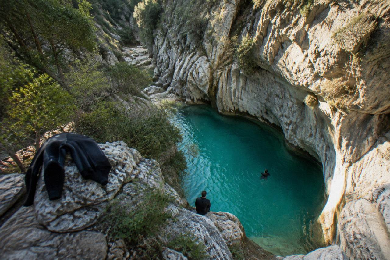 Narrow limestone canyon with turquoise water pooled between tall rock walls