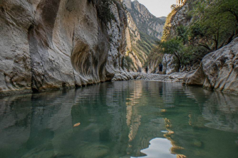 Canyon pool between polished rock walls with still green water
