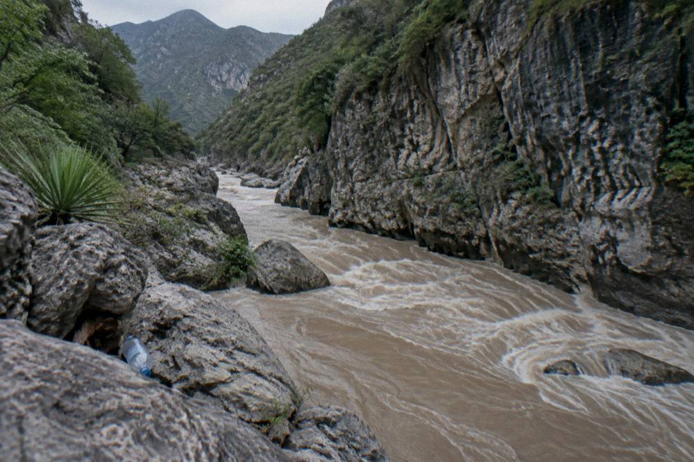 Muddy river water surging through a narrow rocky canyon