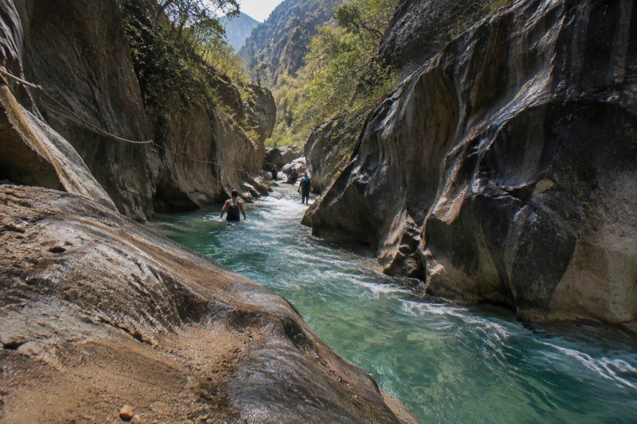 Narrow limestone canyon with clear water flowing between dark rock walls
