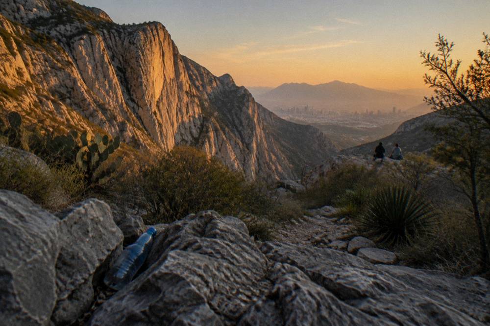 Golden sunset light striking the tall cliffs of a desert canyon near a city skyline