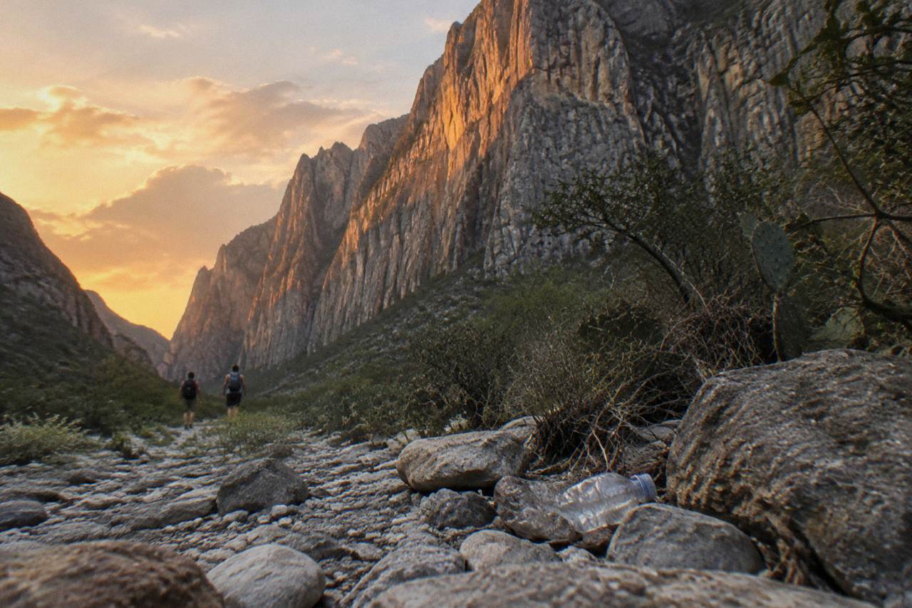 Tall gray limestone cliffs of La Huasteca canyon rising above scrubland at sunset