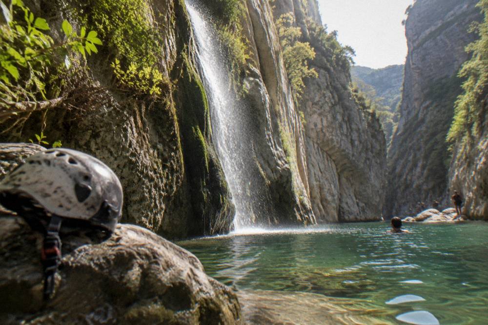A waterfall dropping between mossy rock walls into a deep pool
