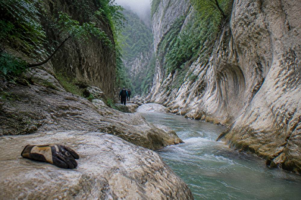 A deep narrow canyon passage with water flowing between smooth stone walls
