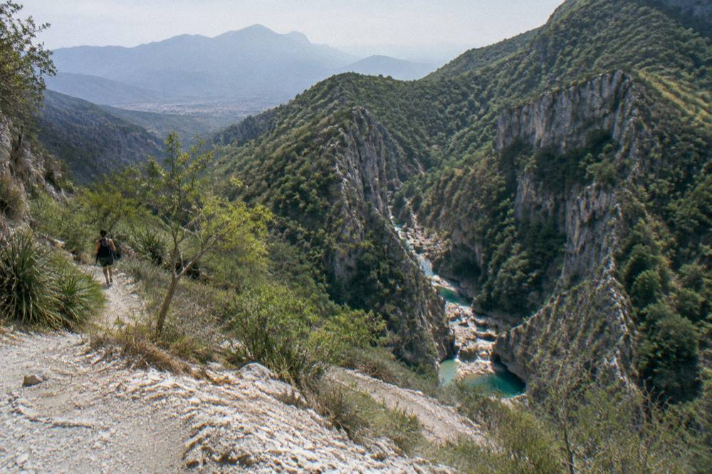 A wide view of forested mountains above a river gorge at midday