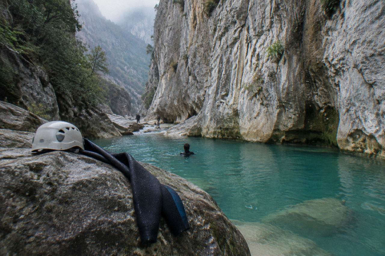 A narrow limestone canyon with turquoise water pooling between tall rock walls