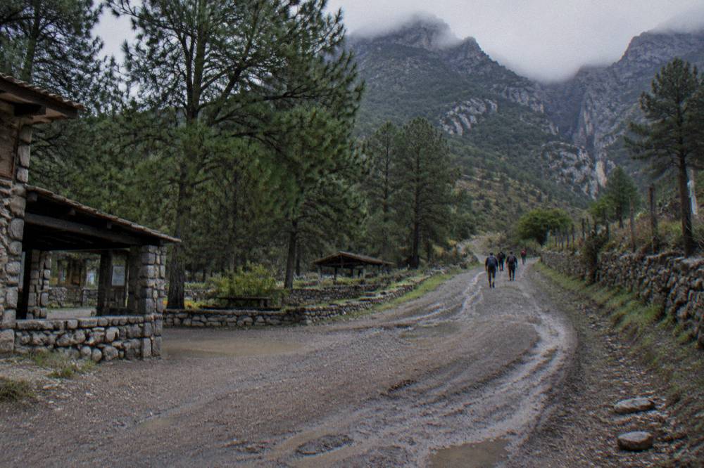 Village road winding toward forested mountains at the Potrero Redondo trailhead area