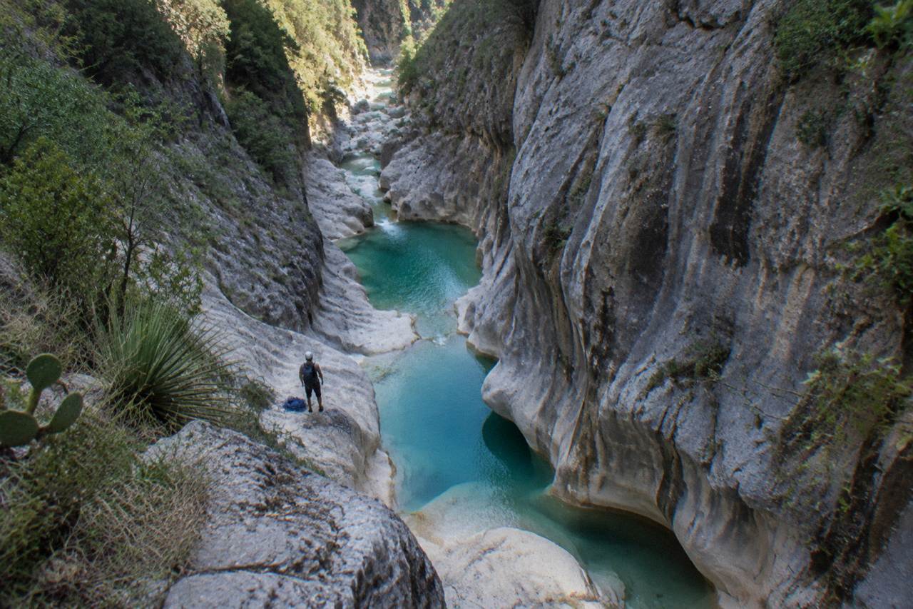 Narrow limestone canyon with turquoise water pooling between rock walls