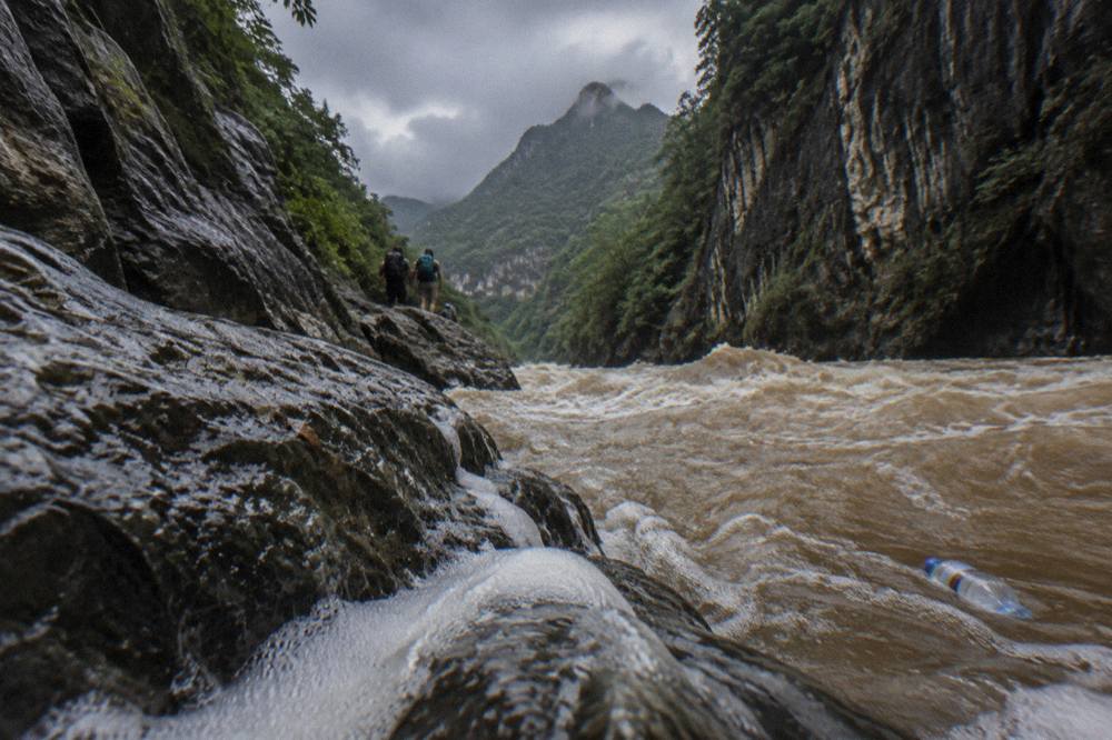 Muddy brown water rushing between canyon walls after heavy rain