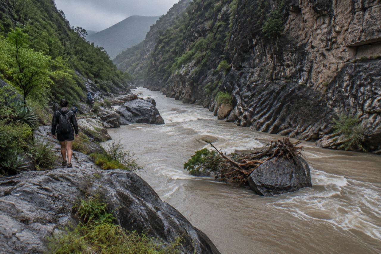 Swollen river flowing through a narrow canyon with dark rock walls