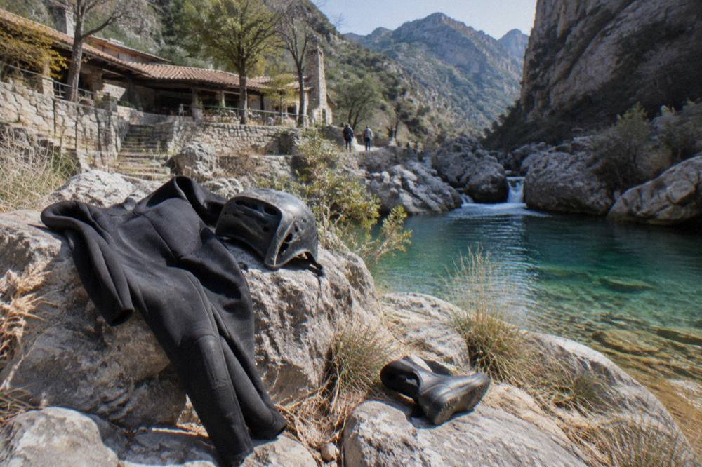 Wetsuit and helmet laid out on rocks beside a canyon pool