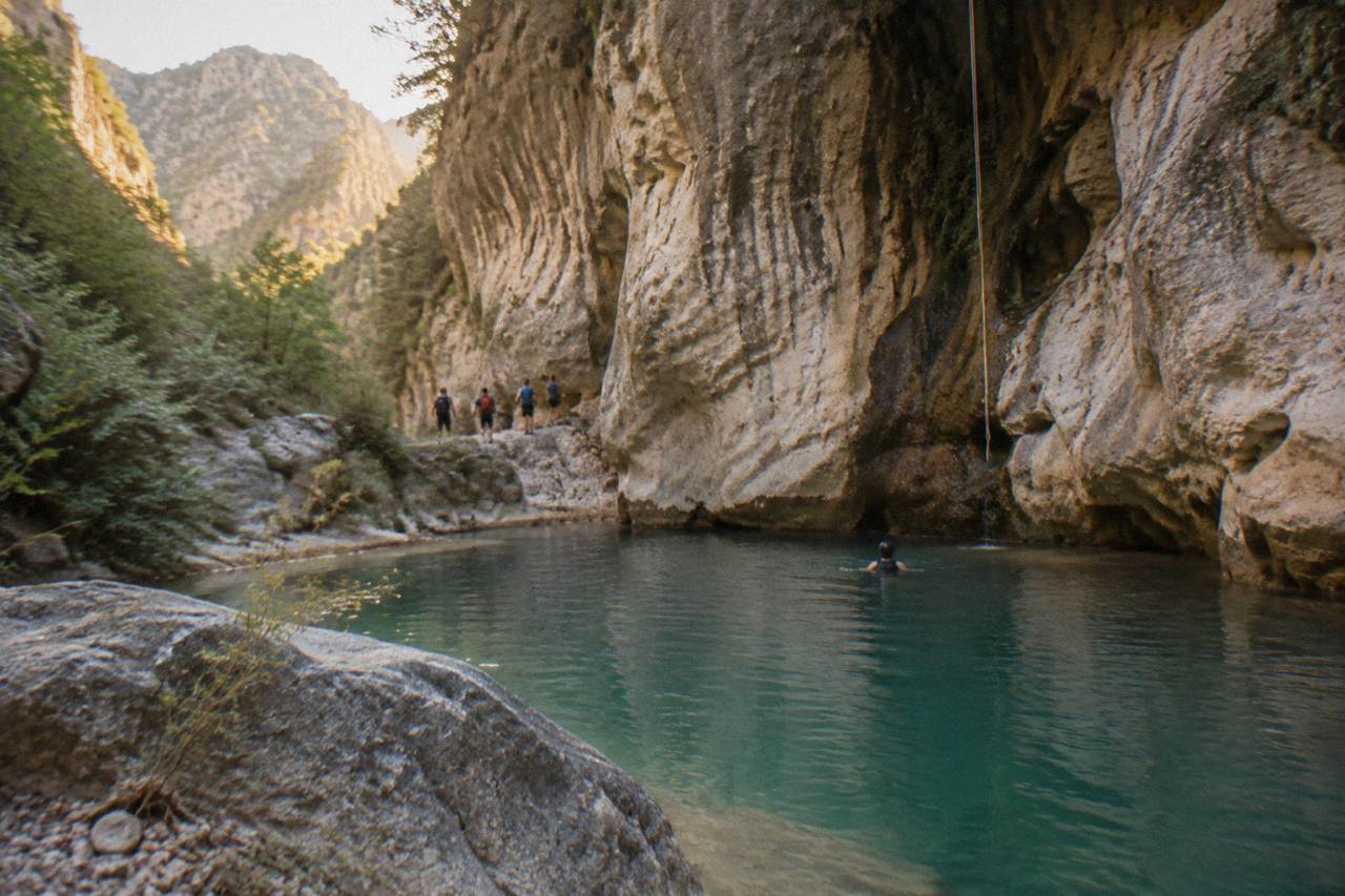 Narrow limestone canyon with turquoise water pooling between tall rock walls