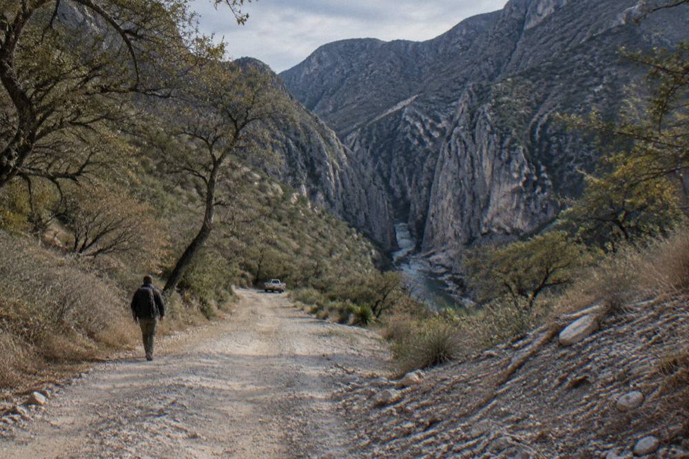 Dirt access road winding down toward a mountain canyon entrance