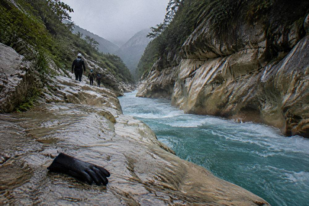Swift turquoise water rushing between smooth rock walls in a narrow canyon passage