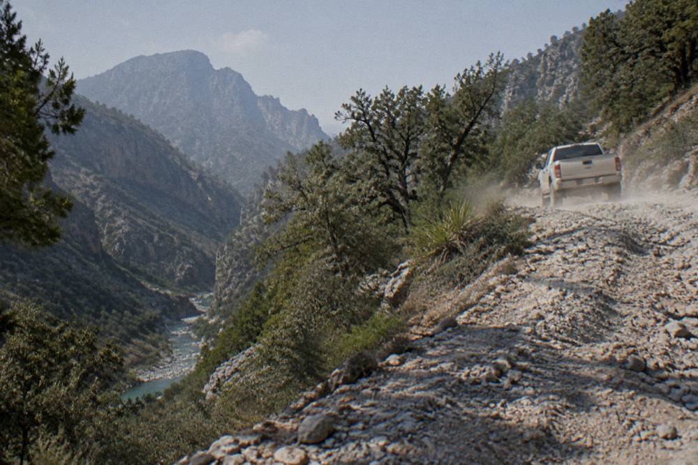 Four wheel drive vehicle on a rocky mountain track above a forested canyon