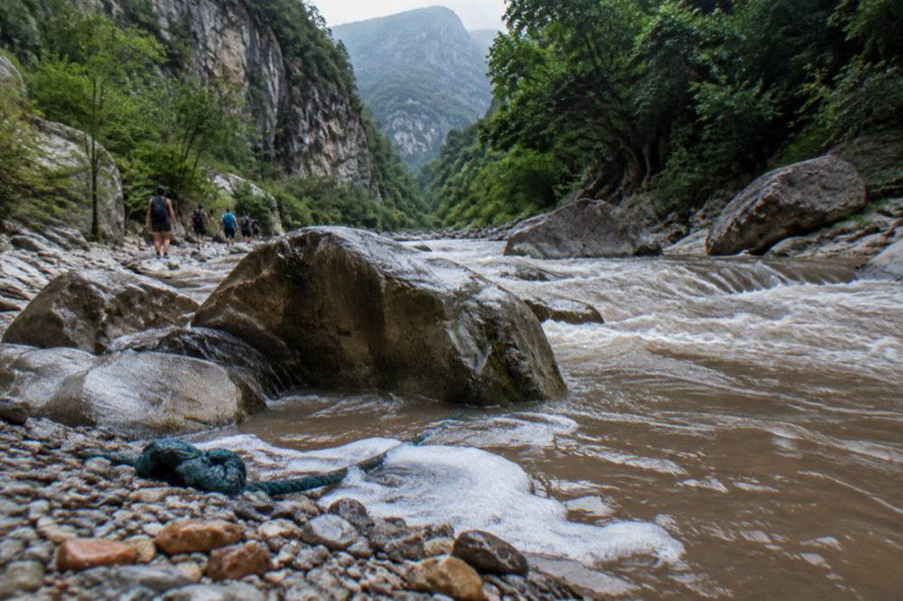 Swollen brown river rushing through a rocky canyon after heavy rain