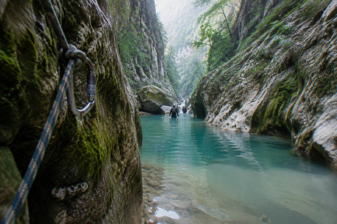 Narrow limestone canyon with turquoise water pooling between mossy rock walls