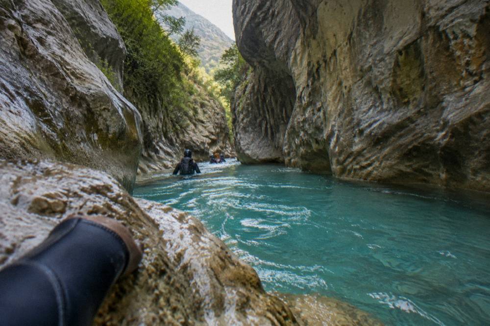 Narrow canyon passage with turquoise water between tall rock walls