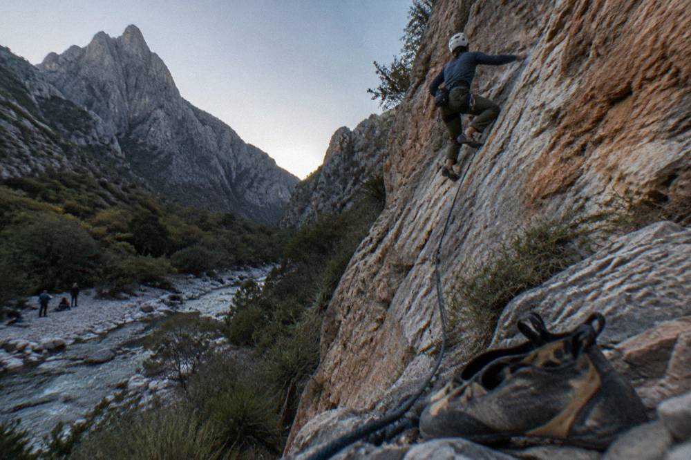 Climber on a bolted limestone route with a long wall stretching above