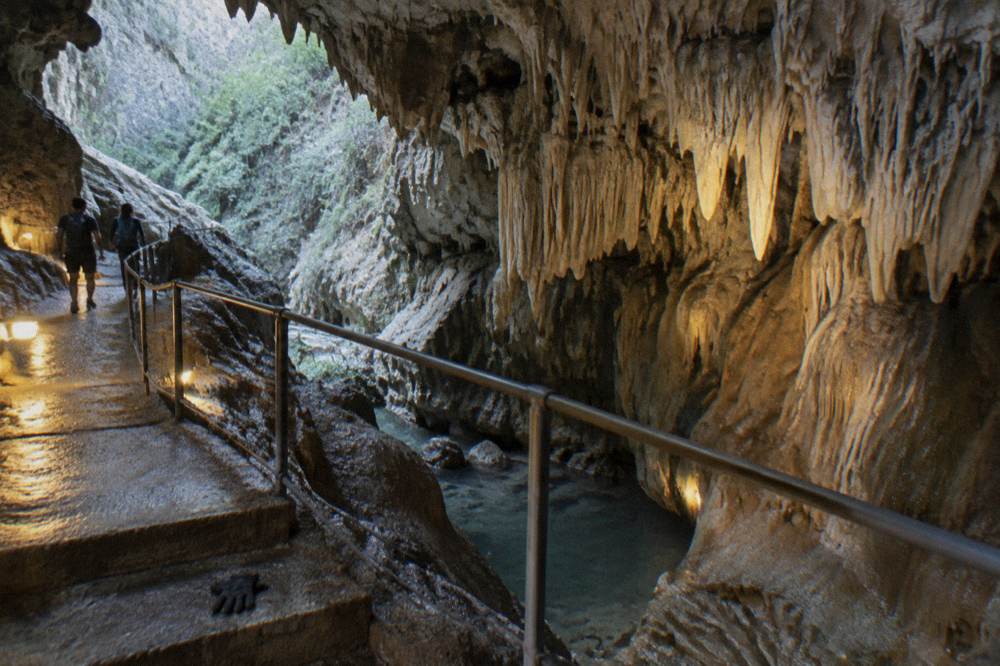 Cave chamber with stalactites lit by walkway lights