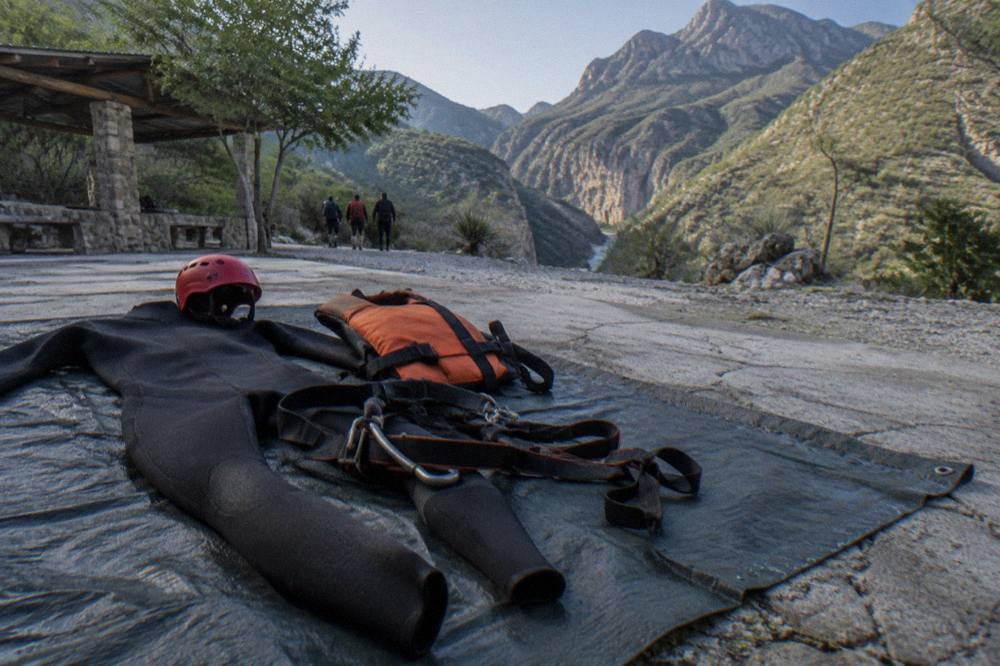 Helmet, harness, wetsuit and life vest arranged on a bench before a canyoning tour