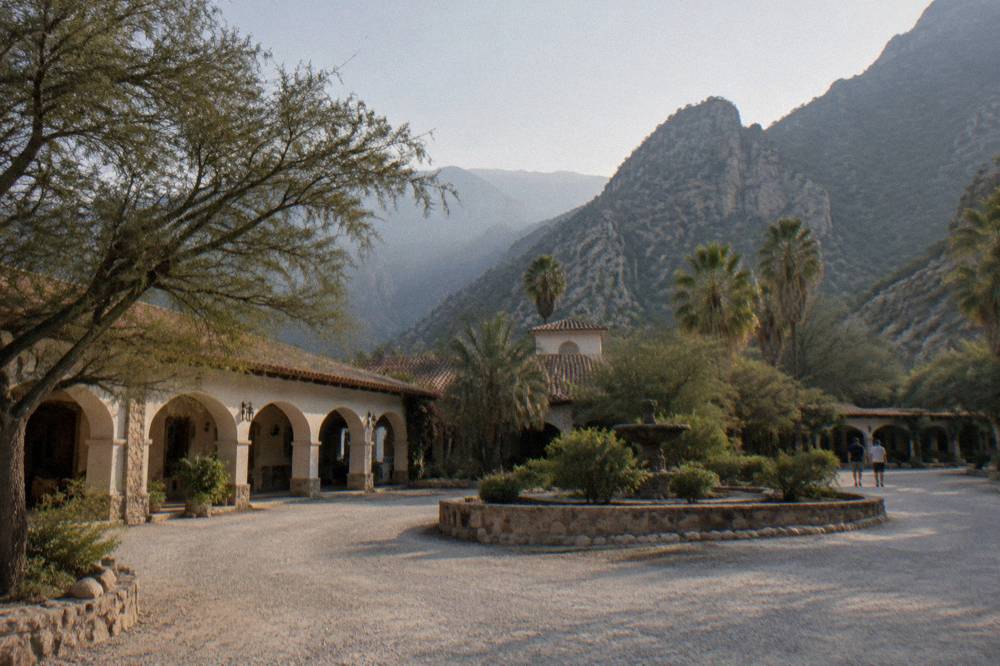 Parking area and roundabout in front of a hacienda-style hotel in Santiago
