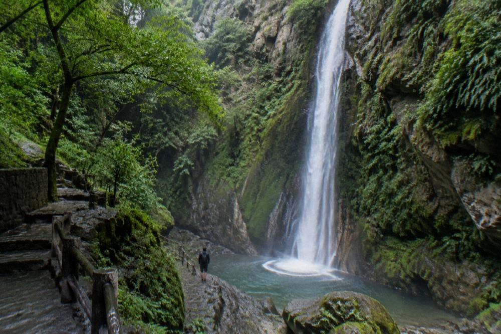 Long ribbon of waterfall falling into a green forested gorge